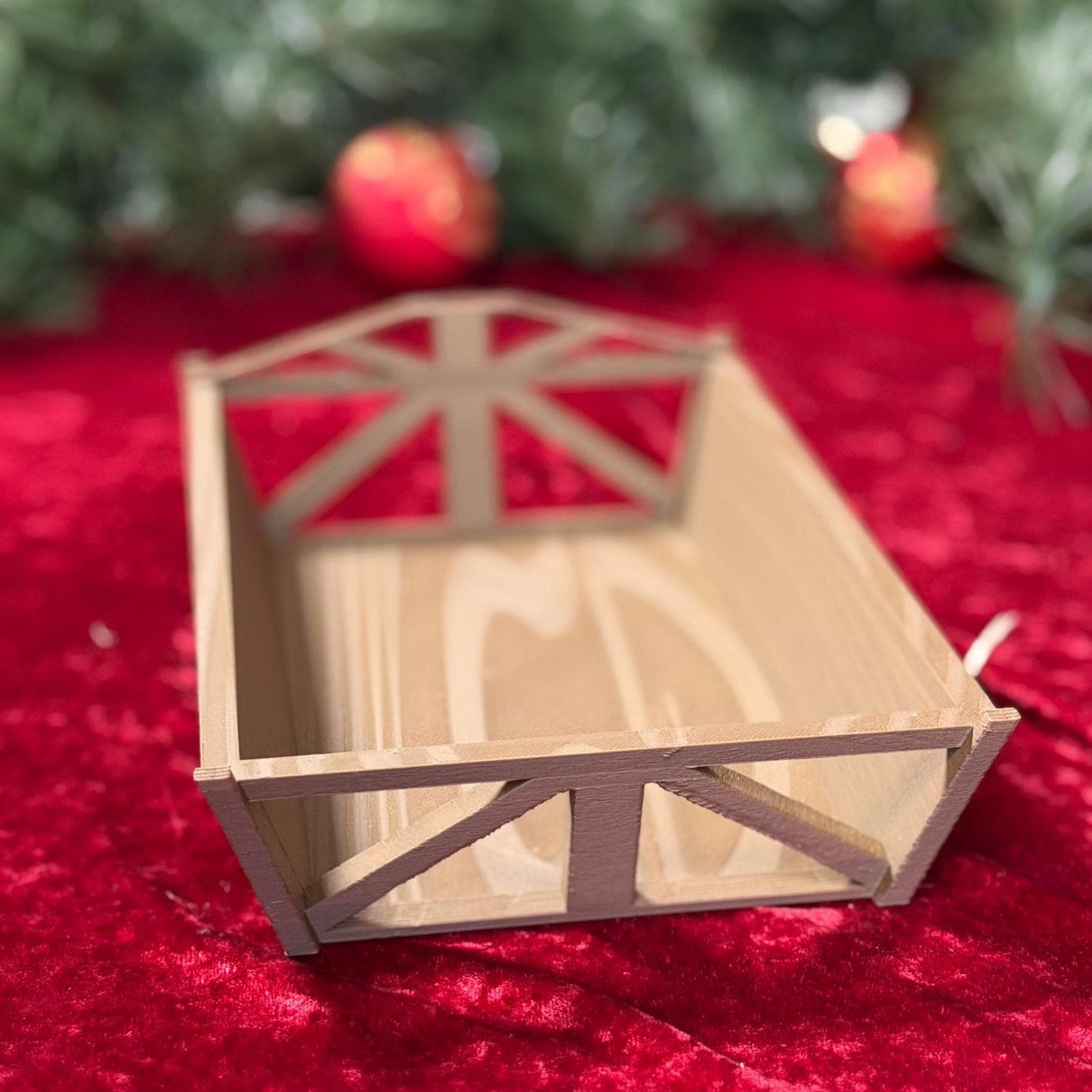 Wooden nativity manger scene by St. Augustine Prints, featuring figurines of Mary, Joseph, baby Jesus, and animals in a rustic setting.