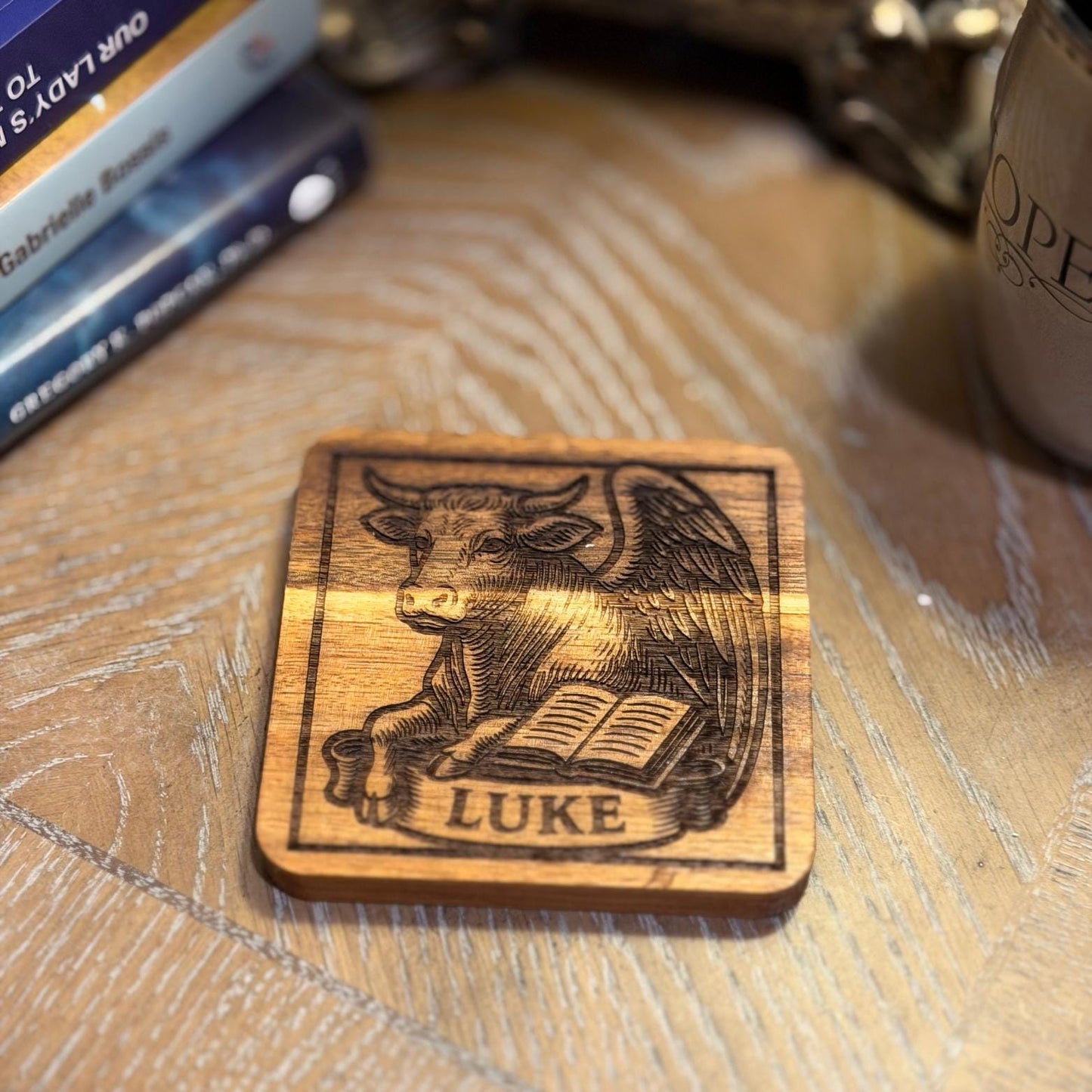 Wooden evangelist coaster set with engraved religious design, featuring St. Augustine Prints branding on natural wood coasters.