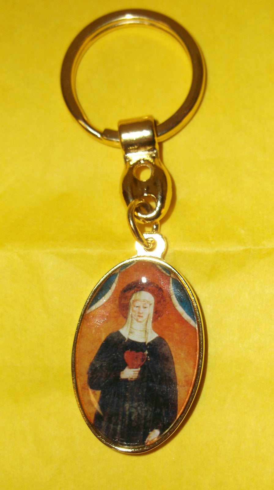 Gold tone Saint Clare of Montefalco and Sacred Heart medal keychain with religious imagery, featuring detailed Christian symbols.