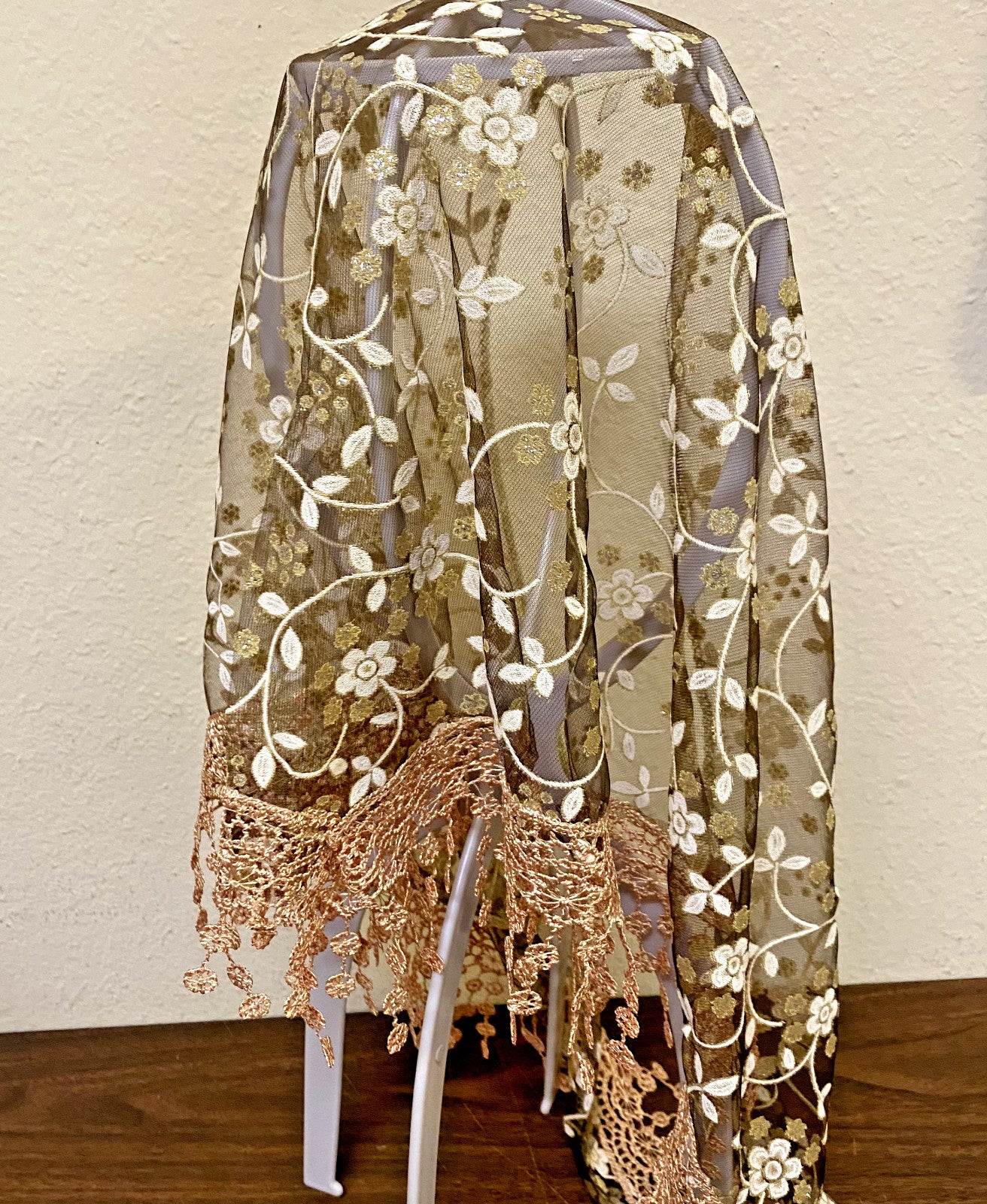 Women's brown lace church veil with delicate floral lace details, draped over a neutral background.