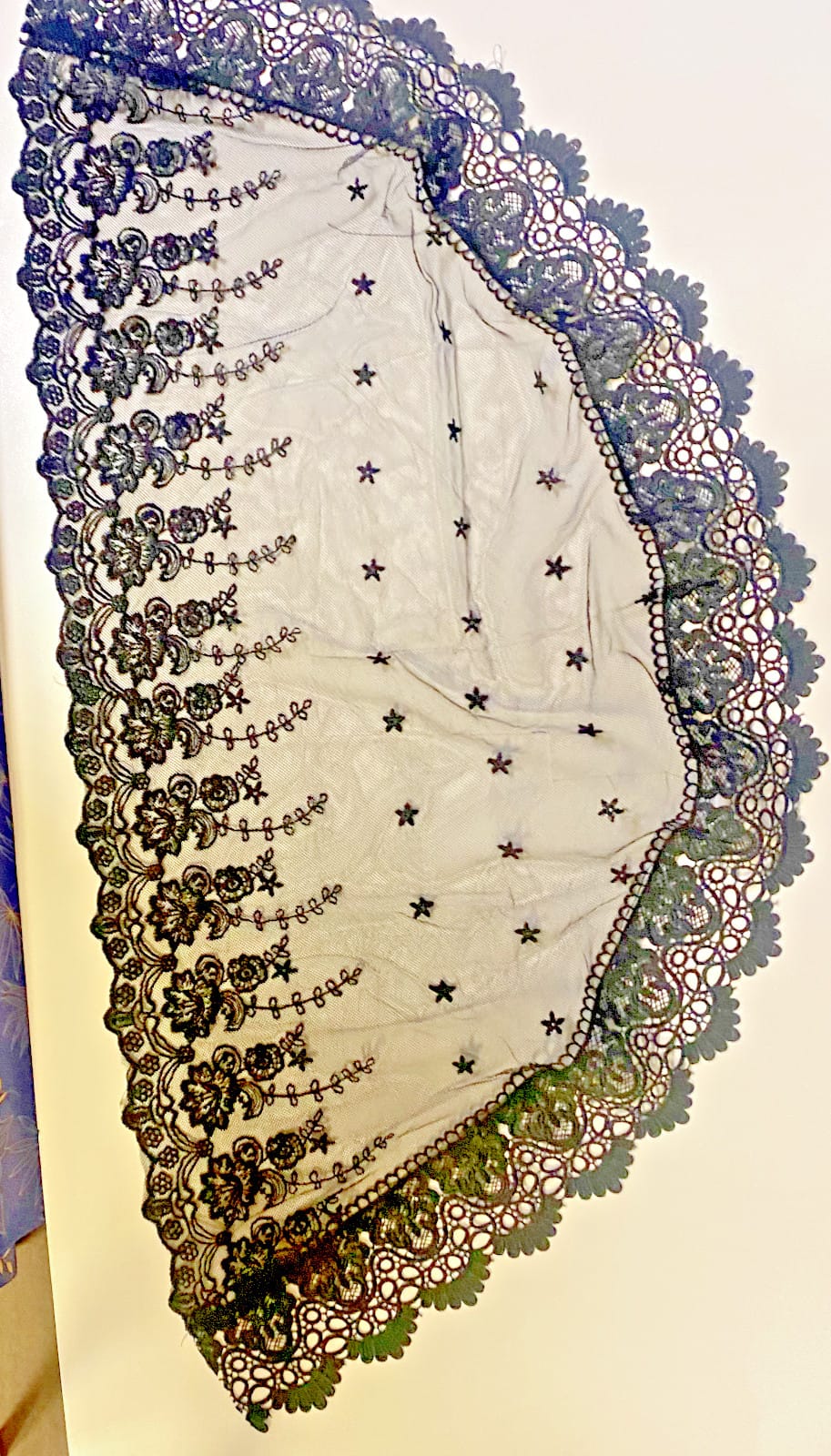 Black lace women's church veil draped over head, lightweight chiffon fabric, delicate lace trim, suitable for religious ceremonies.
