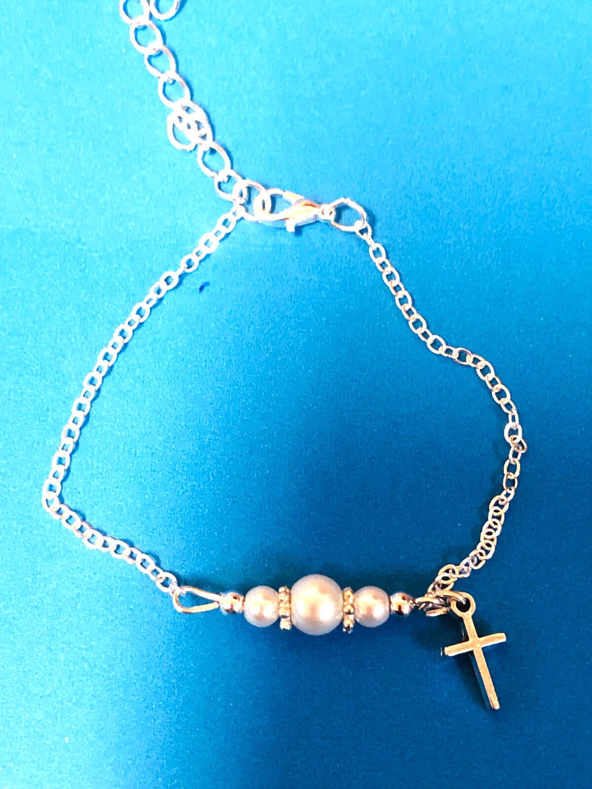 Children's glass pearl bracelet with cross charm, adjustable 7-inch fashion jewelry by Pearl, featuring delicate glass pearls and a cross pendant.