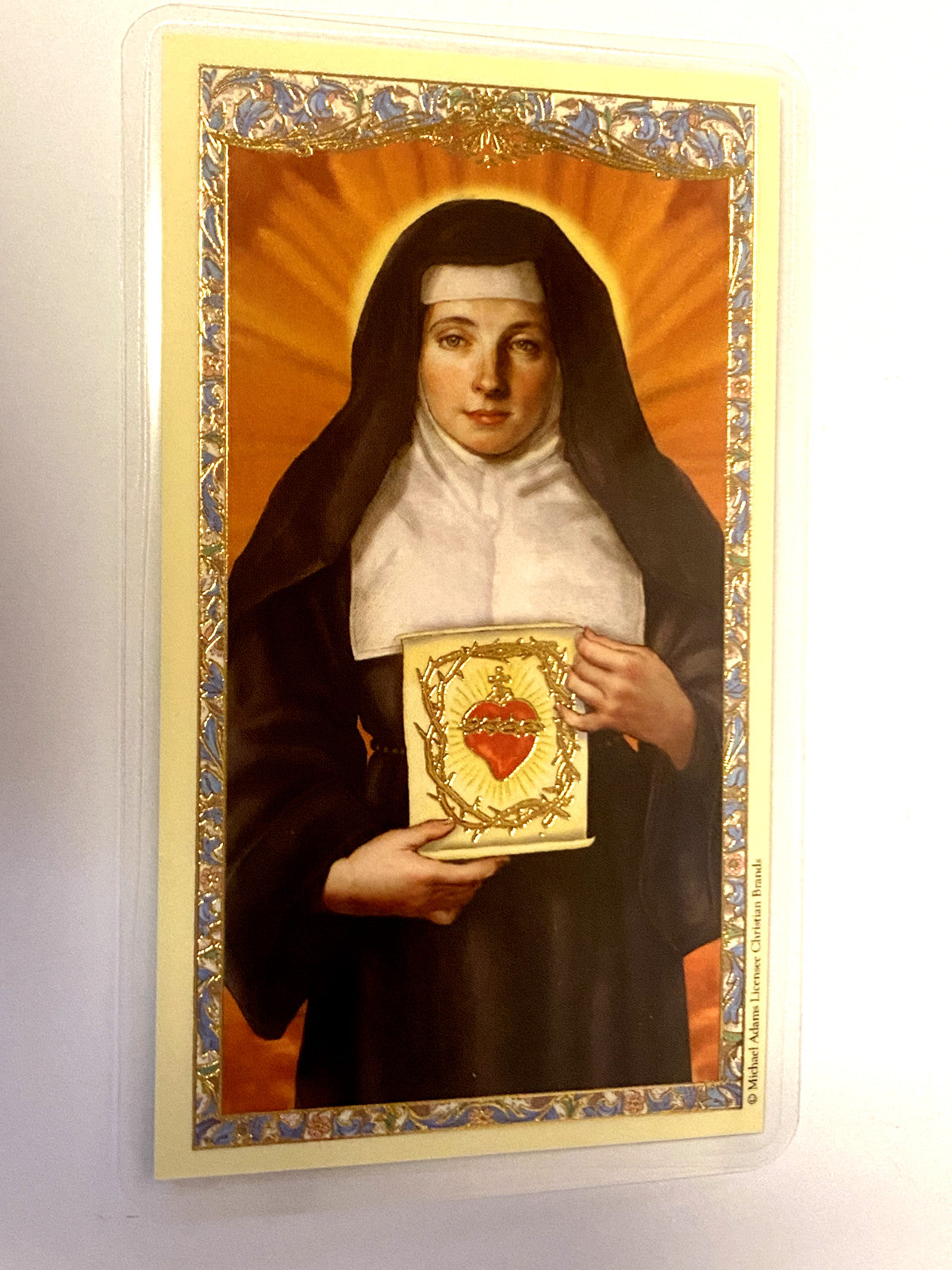 Laminated Saint Margaret Mary Alacoque prayer card by Bob and Penny Lord, featuring religious artwork and prayer text.