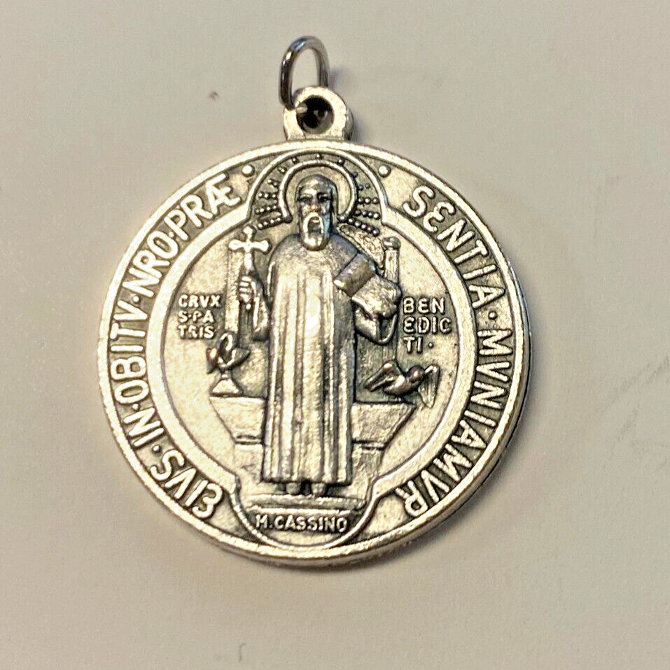 Silver tone Saint Benedict medal with detailed religious design, featuring Christian symbolism, from Bob and Penny Lord collectibles.