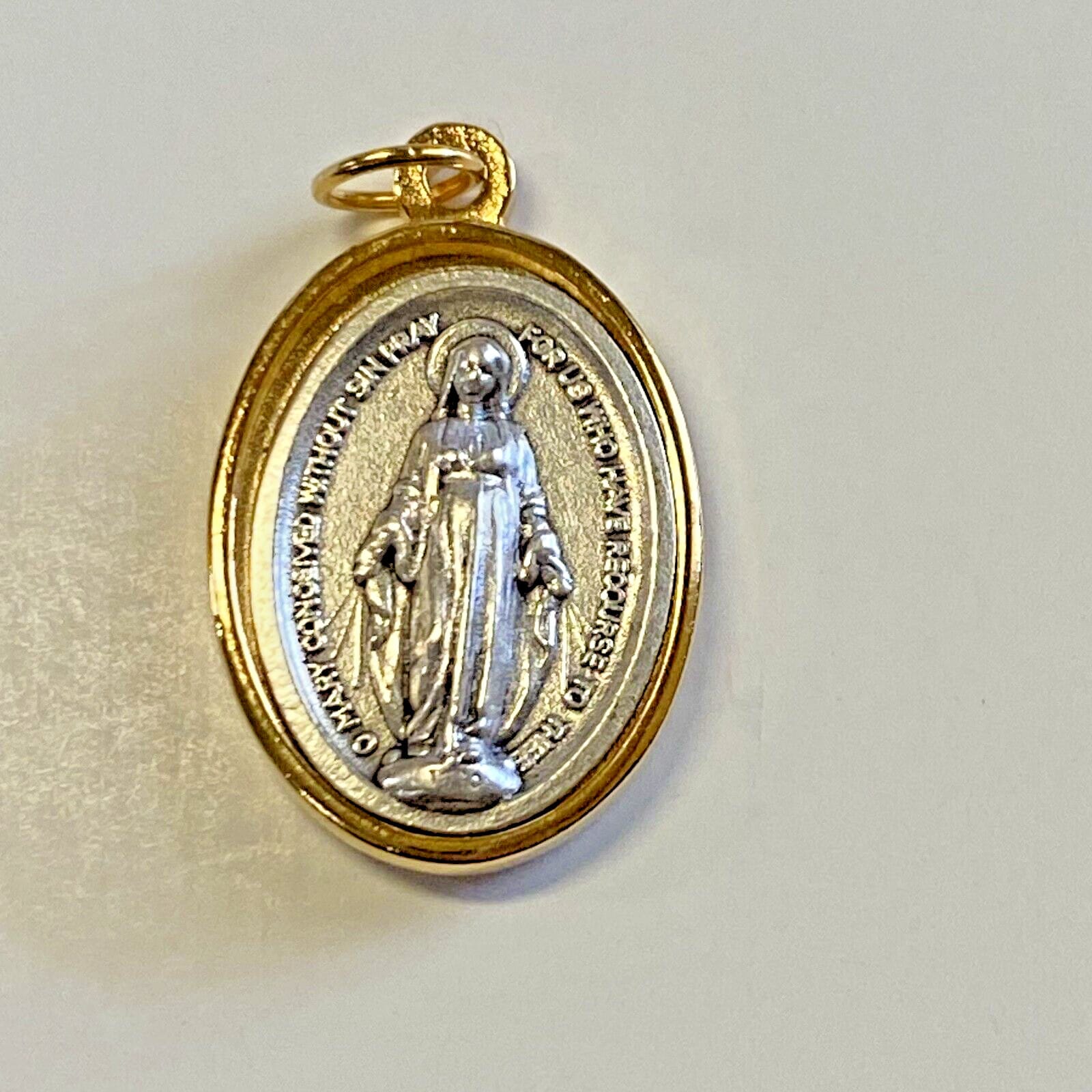 Silver and gold oval Our Lady of the Miraculous medal, Christian religious collectible with detailed religious imagery.
