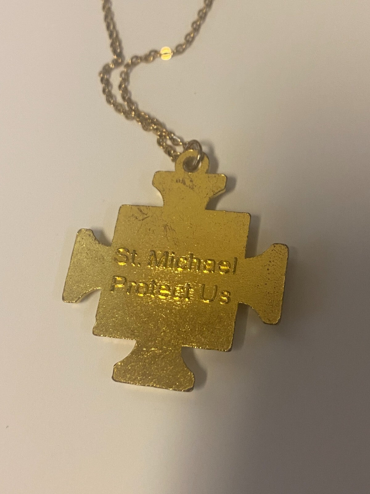 Gold and silver tone Saint Michael the Archangel iron cross pendant featuring detailed religious artwork and intricate design.