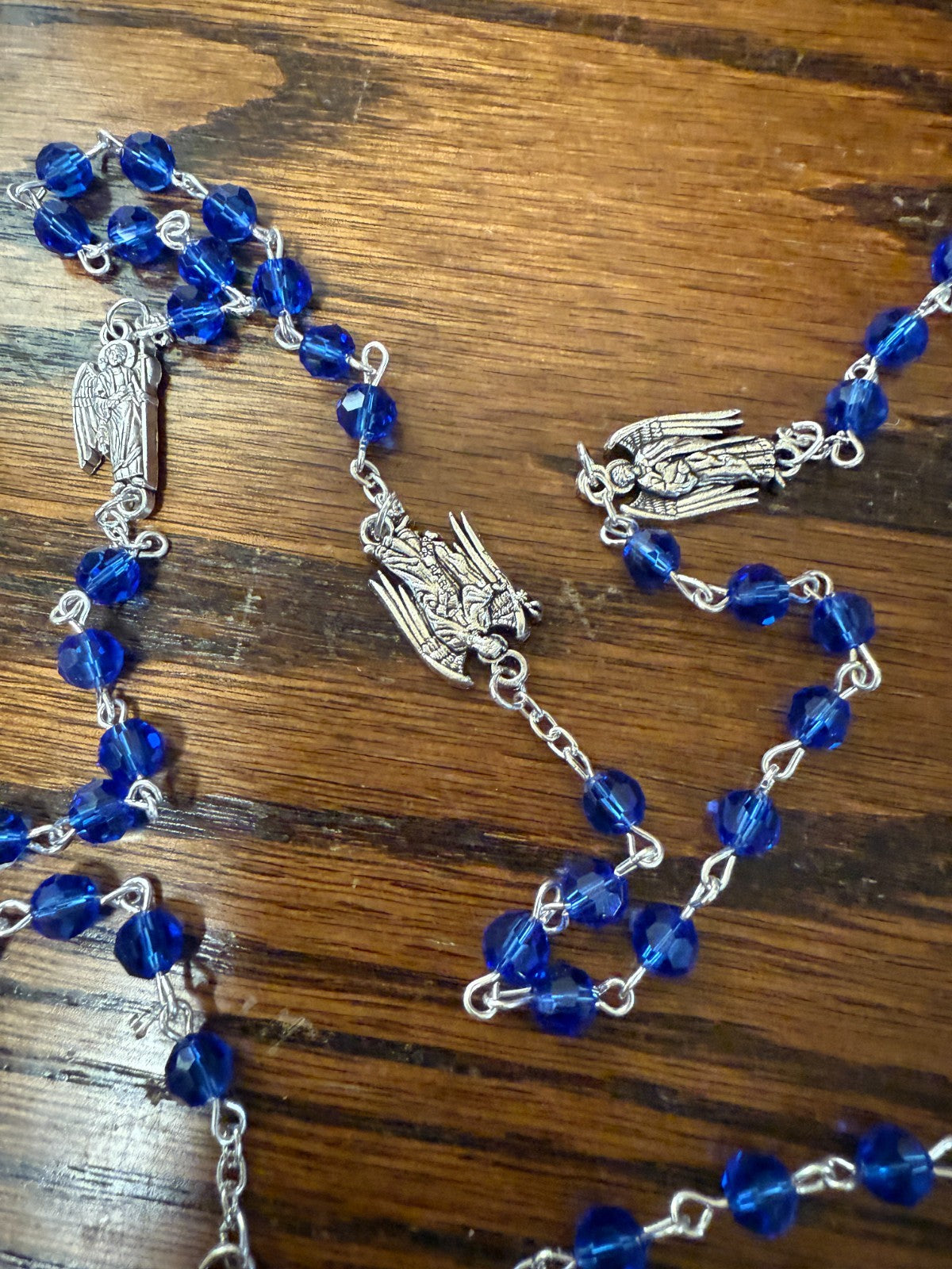 Blue glass beads rosary with Saint Michael and archangels medals, featuring religious Christian symbolism and detailed craftsmanship.