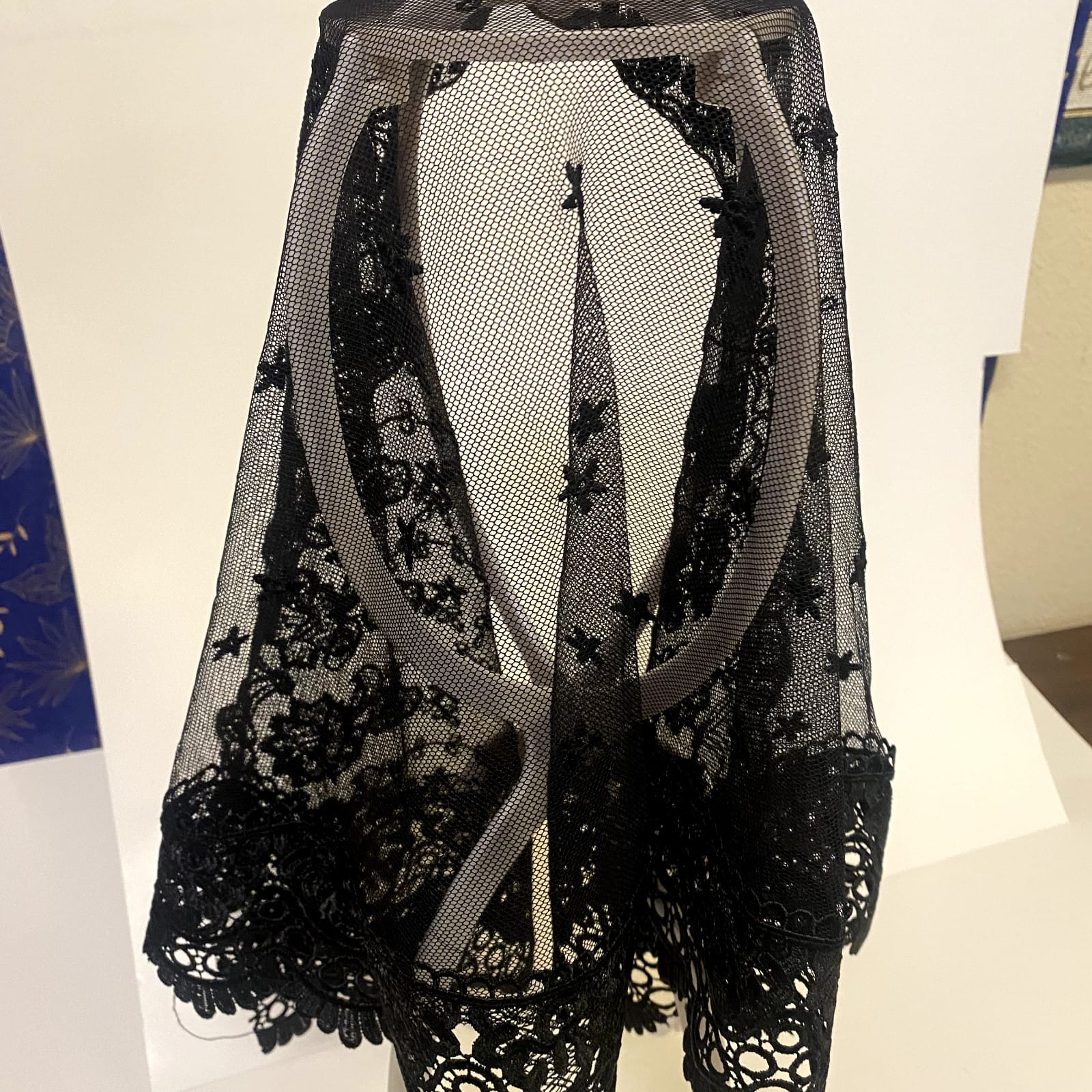 Black lace women's church veil with delicate floral pattern, lightweight and elegant accessory for special occasions.