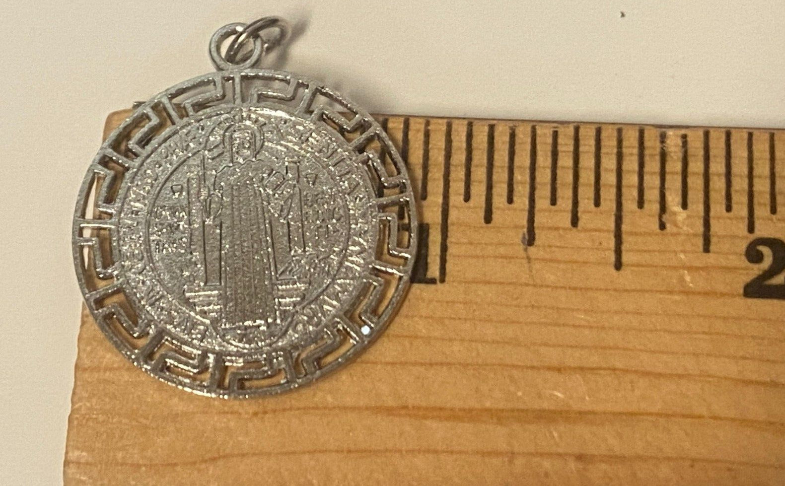 Silver tone Saint Benedict laser-etched medal, 1-inch diameter, Christian religious collectible with detailed design.