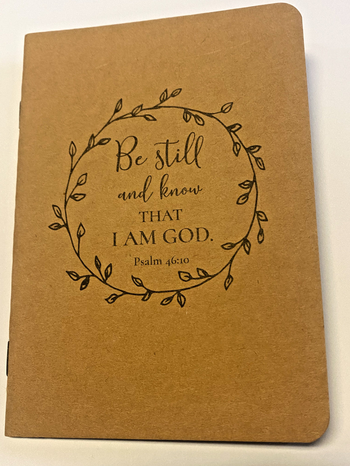 Kraft notebook titled "Be Still & Know that I Am God" by Bob and Penny Lord, featuring religious Christian design and Holy Cards theme.