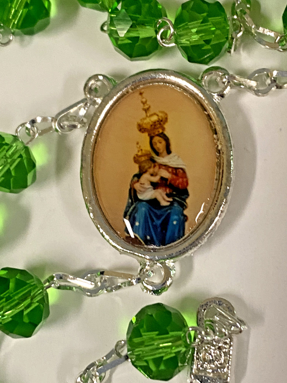 Handmade green rosary featuring Our Lady of Mount Carmel, crafted with beads and a crucifix, from Colombia by Bob and Penny Lord.