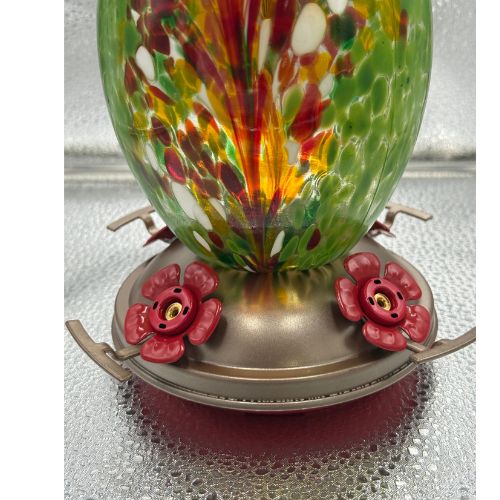 Hand blown glass hummingbird feeder with a vibrant green and red floral design, featuring four feeding ports.
